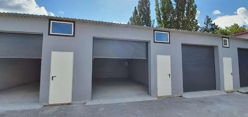 Reihe grauer Lagerboxen mit Rolltoren, weißen Eingangstüren und Fenstern
